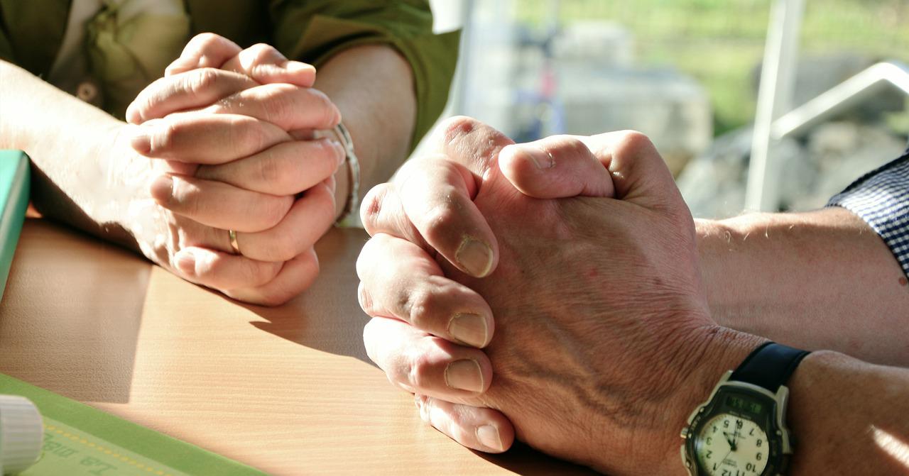 A man and woman with their hands crossed together on a table.